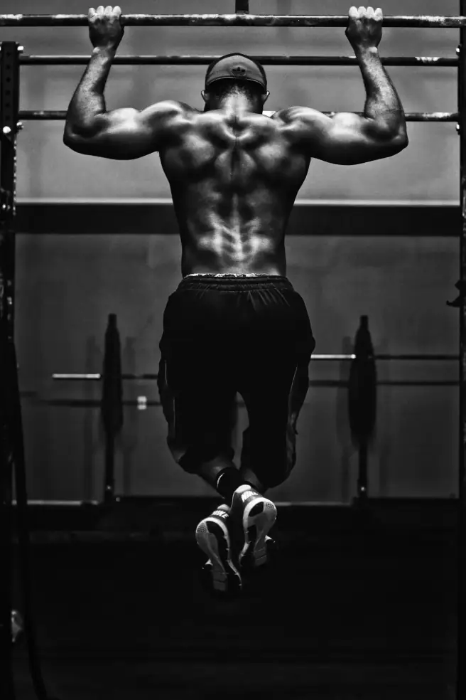 Athlet trainiert Pull-ups in einem dunklen Gym